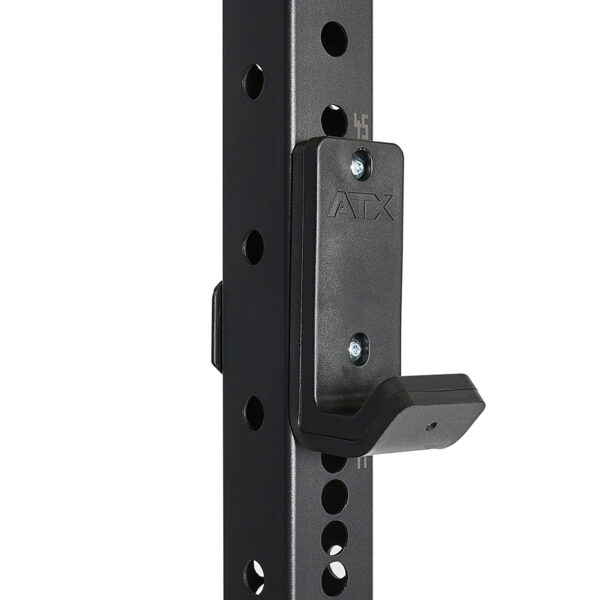 A close-up shows the ATX® logo on a black metal bracket attached to a perforated pole from the ATX® Power Rack 755 Short Distance. The bracket, designed for holding weights or gym equipment, connects to the pole with numbered holes for adjustable positioning.