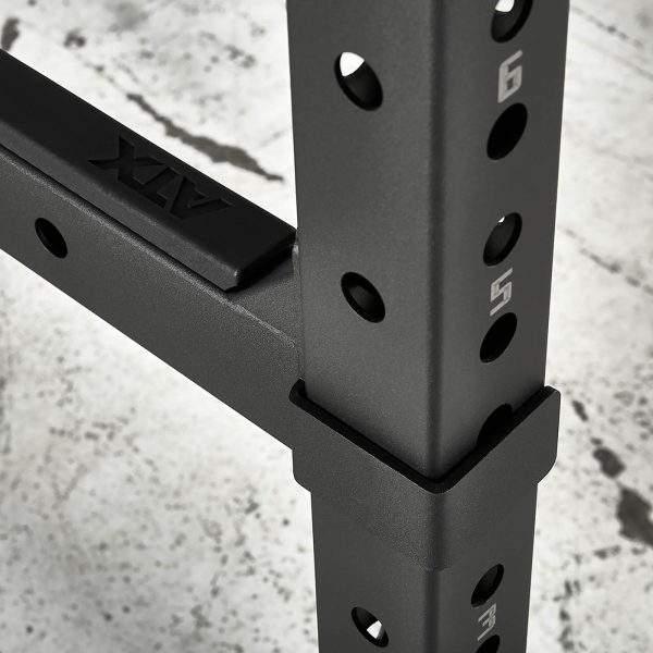 Close-up of the ATX® Power Rack 770 XL SET, featuring numbered holes for height adjustment and a matte finish. The ATX logo is visible, while the concrete floor beneath shows signs of use.