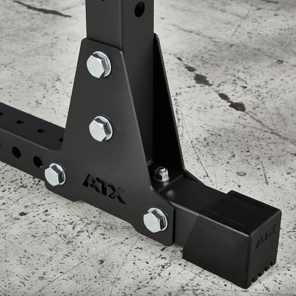 Close-up of a sturdy base with bolts and black cap on a textured gray surface, part of the ATX® Power Rack 770 XL SET. The base features several drilled holes for adjustments.