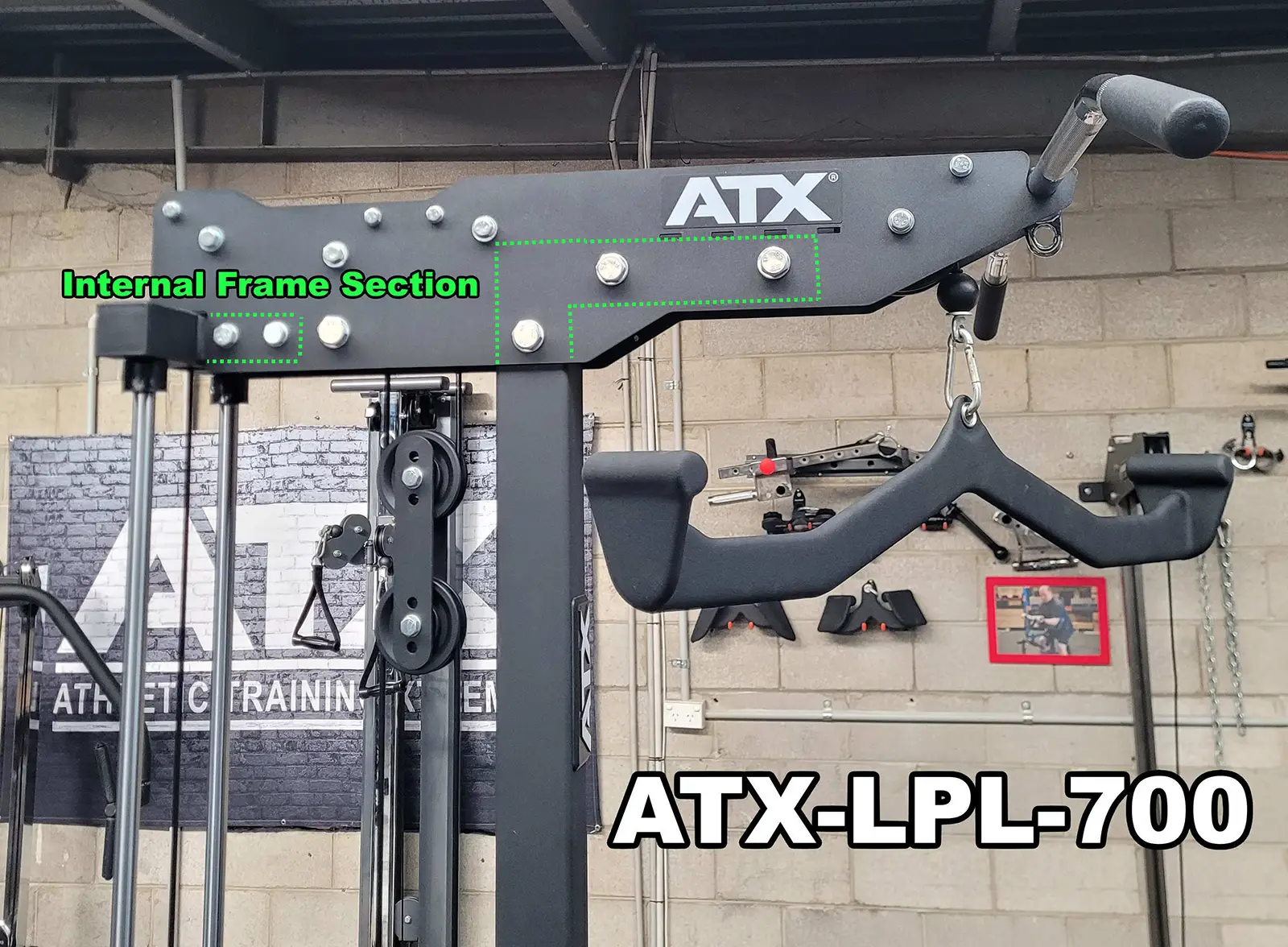 Close-up of an ATX-LPL-700 gym equipment piece, perfect for lat pulldown and row exercises. The image highlights the Internal Frame Section in green text. A brick wall, a logo, and some hanging equipment set the background.