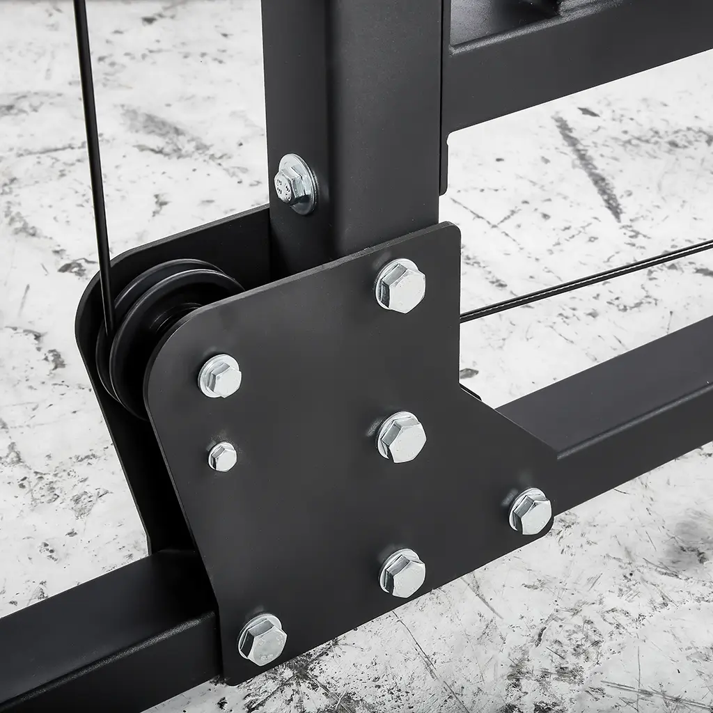 Close-up of the ATX® Plate Loaded Lat Pulldown and Row Machine, featuring a black metal structure with bolts and pulleys, set against a concrete floor. The design showcases connecting rods and cables, emphasizing its industrial style and mechanical components.