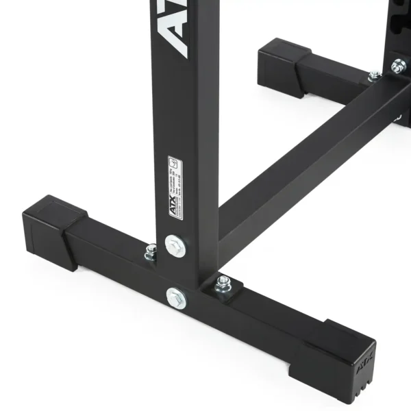 The ATX® Split Squat Stand features a close-up view of its black metal frame with bolts and logo, supported by rubber footings on a white surface. Its design suggests stability and durability.