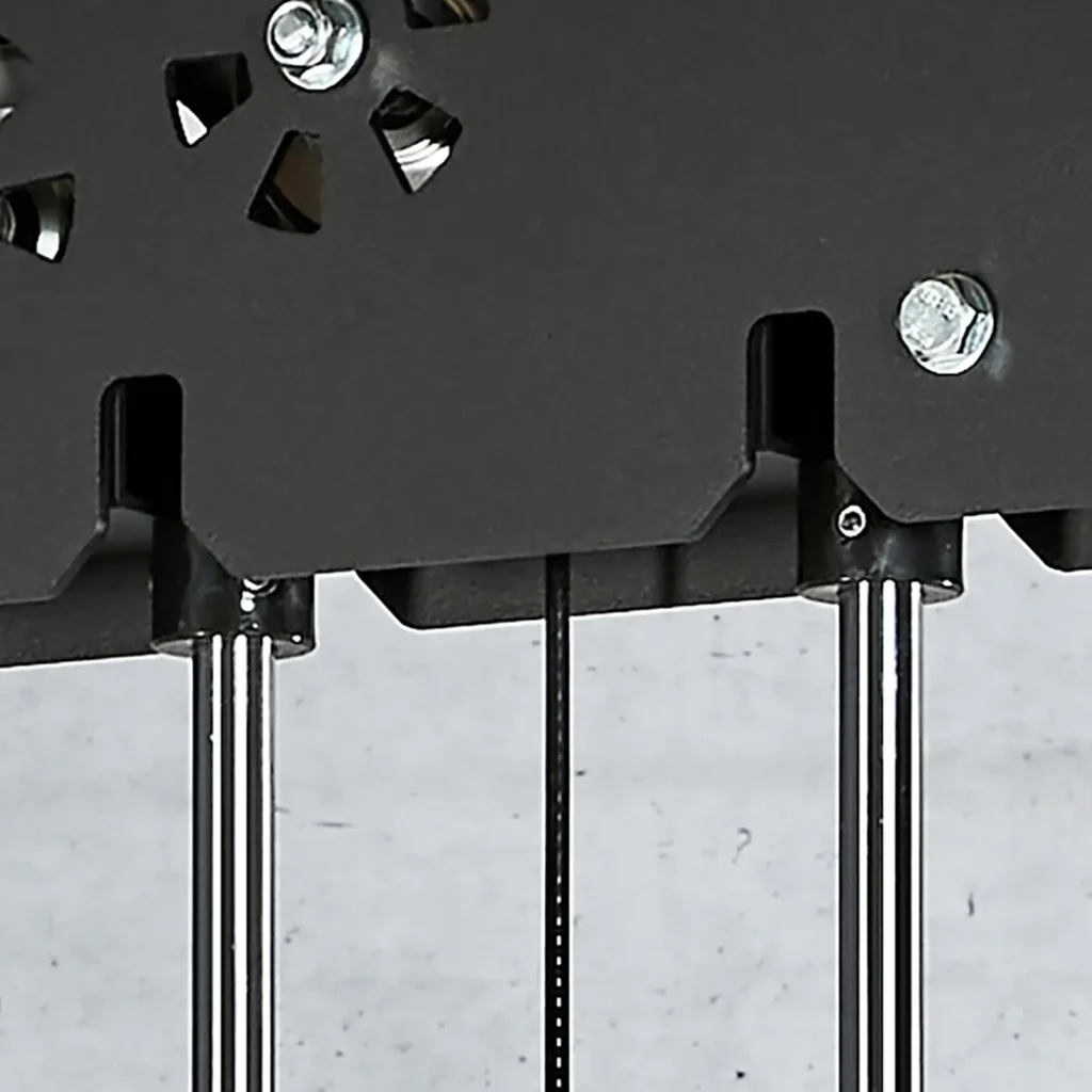Close-up of a mechanical structure featuring three metallic rods and a black panel with bolts, resembling a power cage. Cables intertwine subtly in the design, set against a plain gray background.