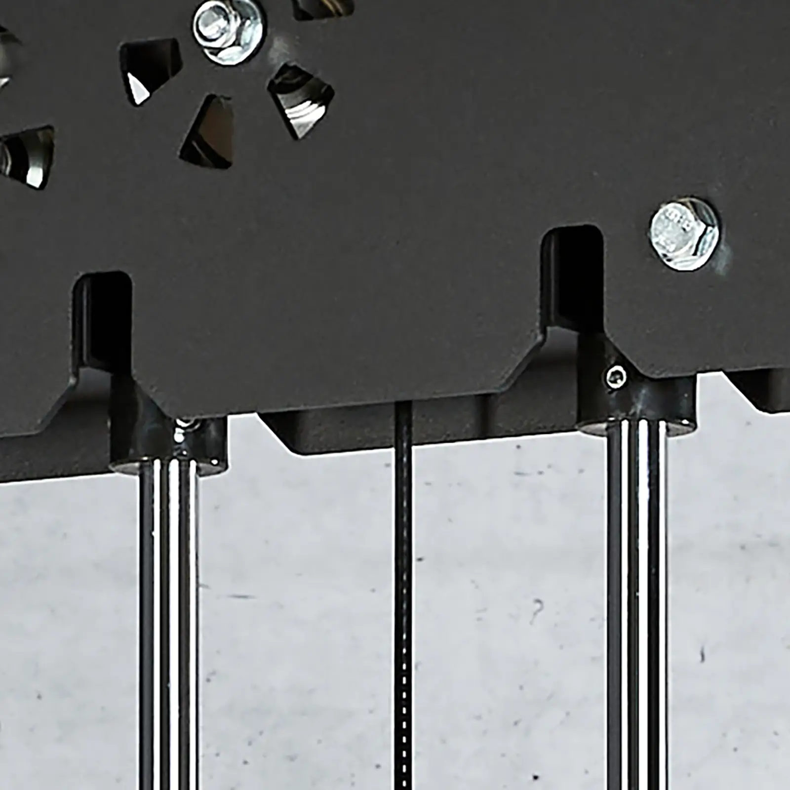 Close-up of a mechanical structure featuring three metallic rods and a black panel with bolts, resembling a power cage. Cables intertwine subtly in the design, set against a plain gray background.