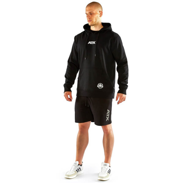 A person in an ATX® Black Hoodie and black shorts stands on a white background, wearing white sneakers with black stripes.