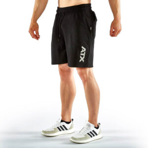 A person wearing ATX® Black Shorts and white sneakers with black stripes stands against a white background.