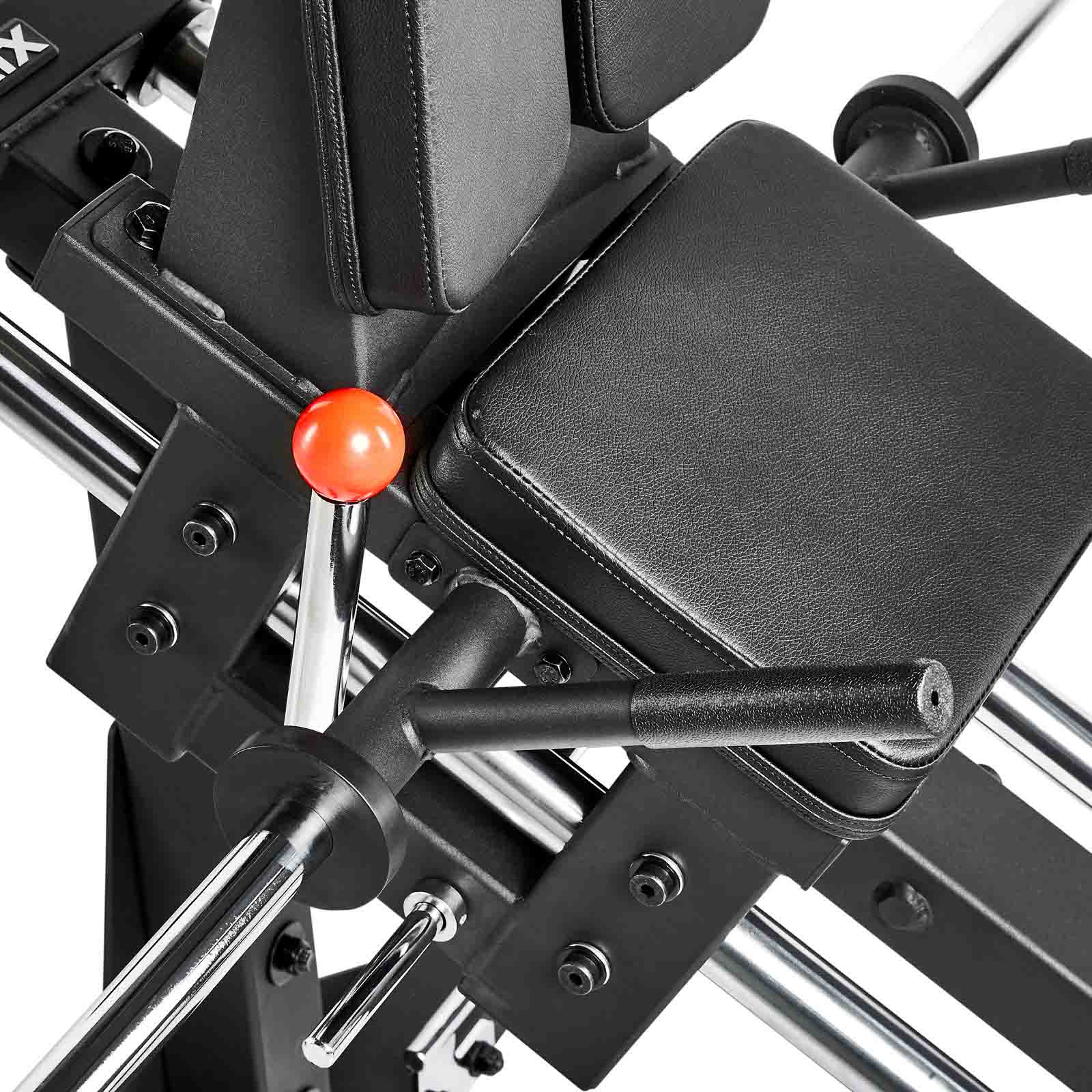 Close-up of a black ATX Compact Leg Press, showcasing padded seats and a metallic frame. Features include handles, a bright red adjustment knob, and various levers for smooth operation.