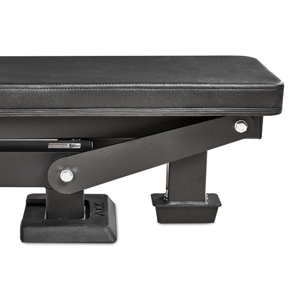 Close-up of the ATX® Trinity Tower 135 kg showing a black padded workout bench with sturdy rectangular legs and metal bolts. The bench features rubberized end caps for enhanced stability.