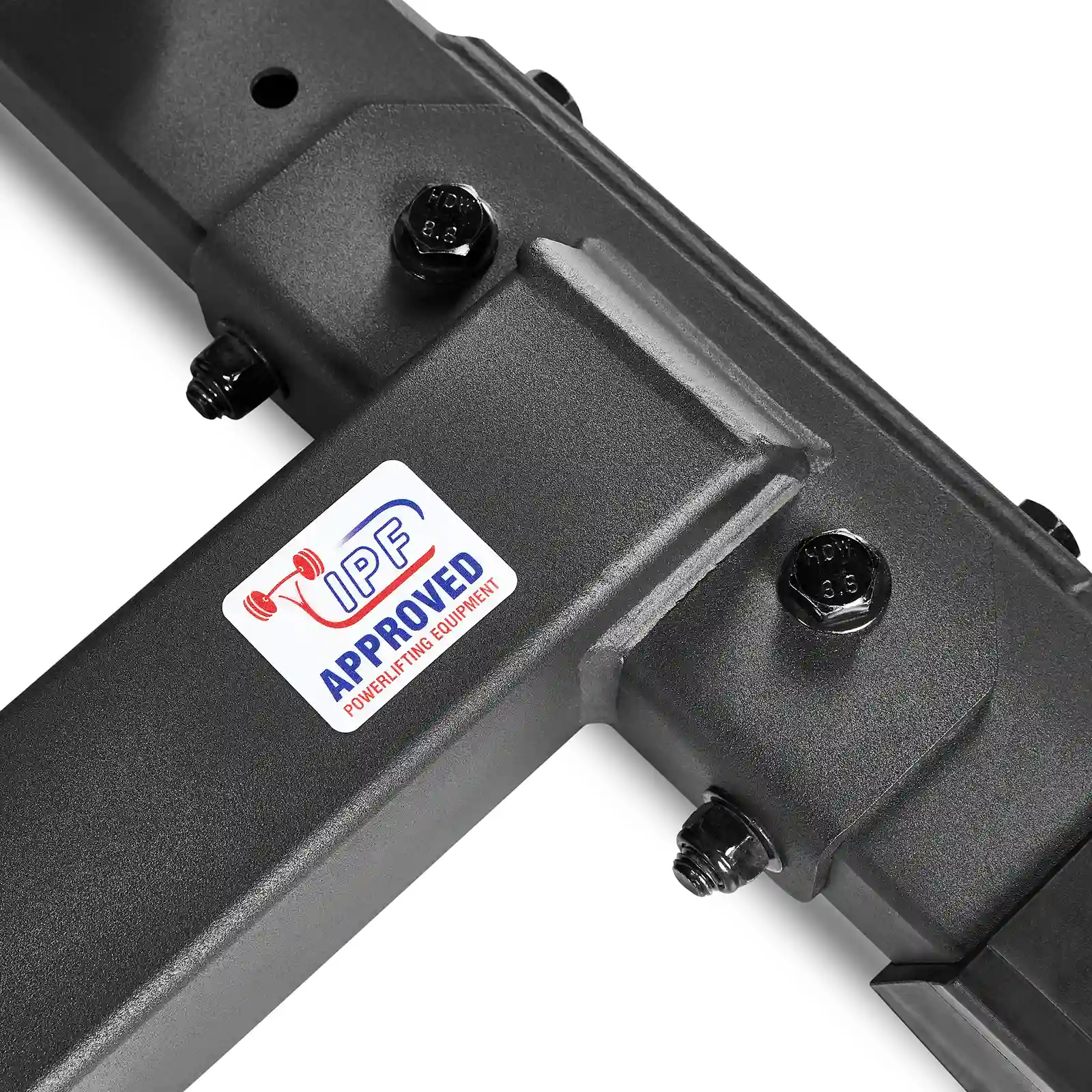 Close-up of a black metal structure, resembling an IPF combo rack, with visible bolts and a sticker that reads IPF Approved Powerlifting Equipment, featuring an image of a red barbell.