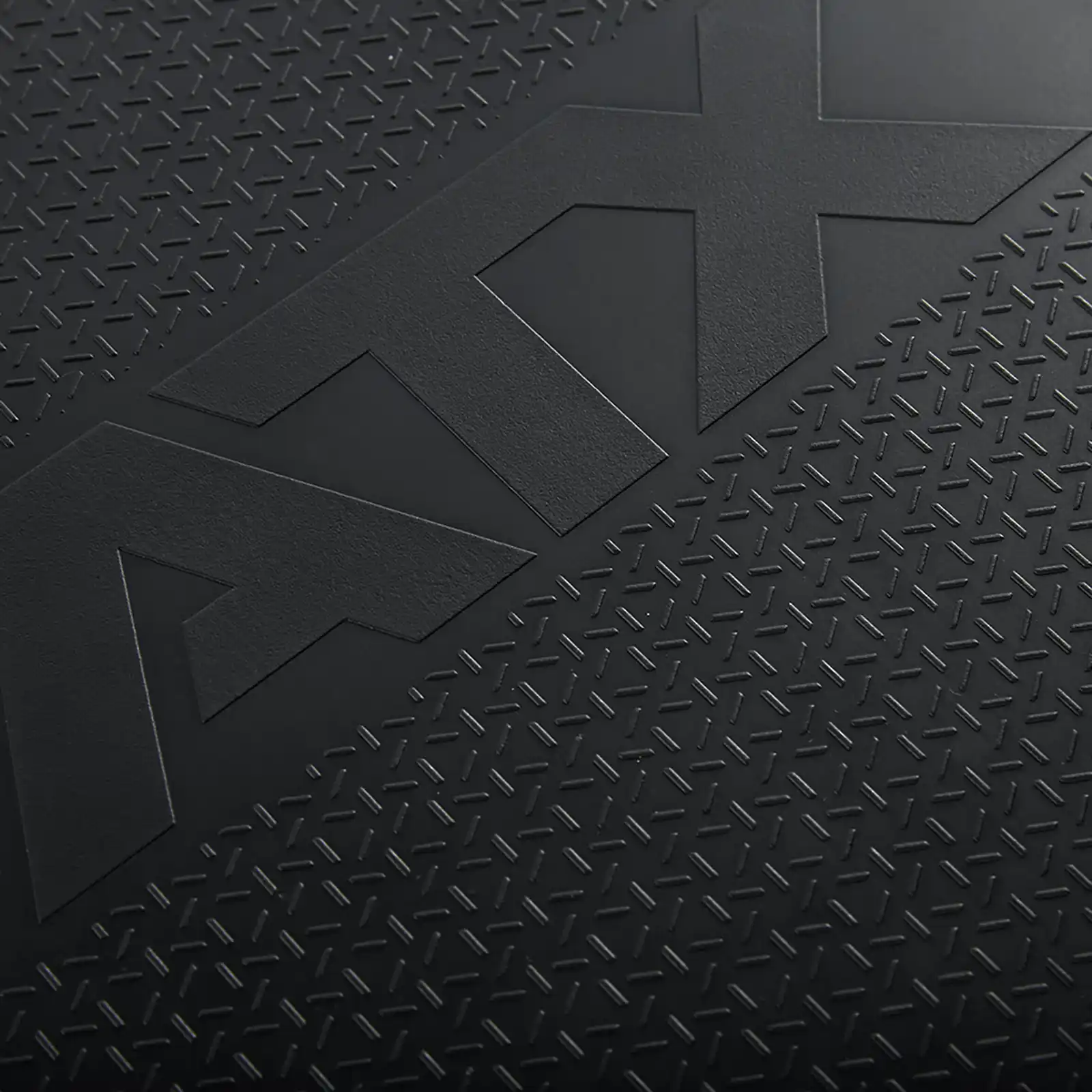 Close-up of a textured black surface with raised diamond patterns, reminiscent of the rugged design found on a competition bench press. The large, embossed letters ATX are prominently displayed, adding contrast to the intricate background.