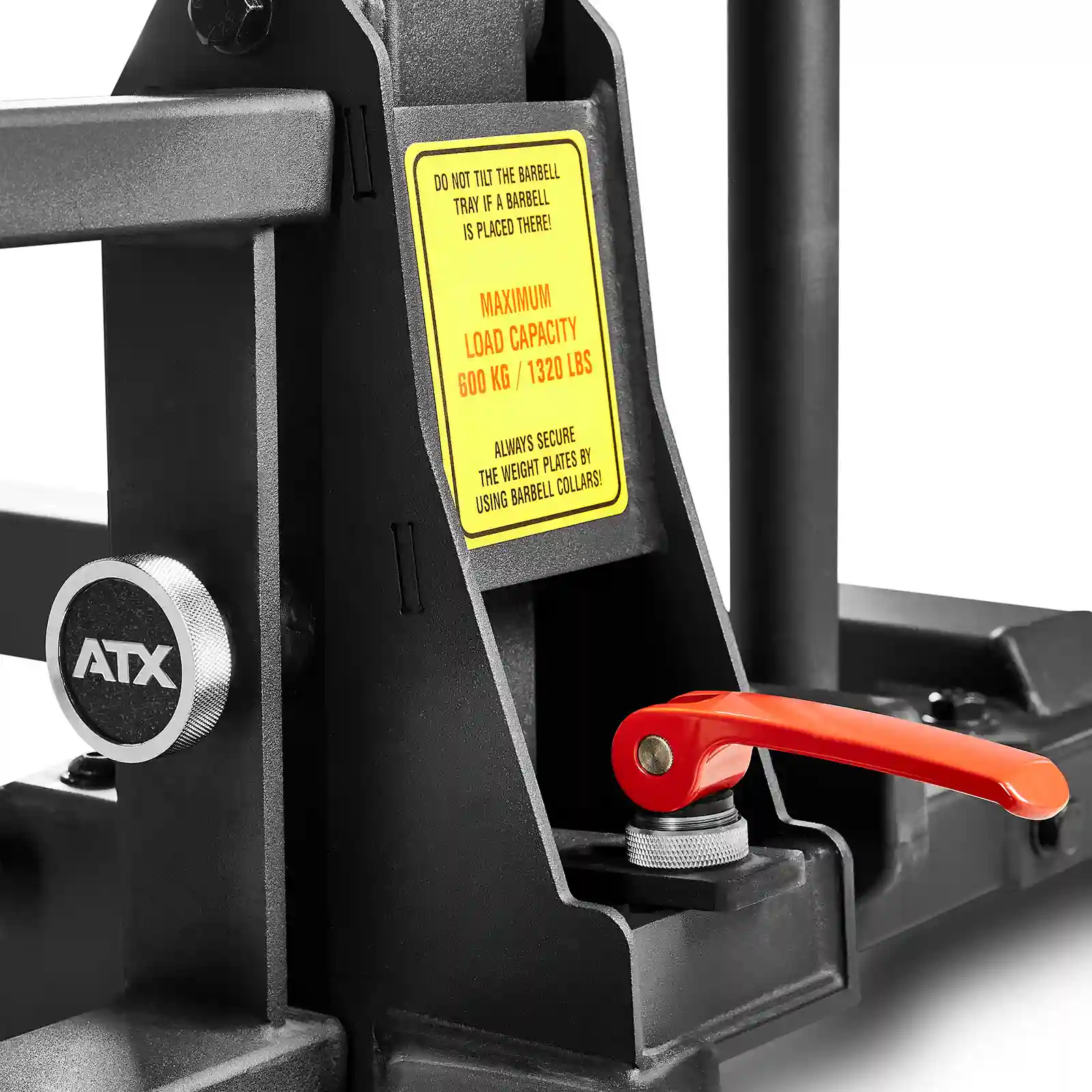 Close-up of a gym equipment with a red handle and a yellow warning label that states a maximum load capacity of 600 kg/1320 lbs. The ATX logo is visible on the metal frame, reminiscent of those used in competition bench press setups.