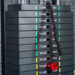 A stack of weight plates on a gym machine features Weight Stack Stickers KG/LBS. A red pin is inserted in the 77 lbs (35 kg) slot, attached with a coiled black cord.