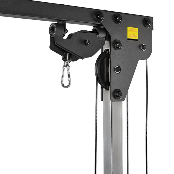 Close-up of an ATX® Cable Crossover 500 198cm in black and silver, showcasing its sturdy pulley system with ropes, metal hook, multiple bolts, and a small yellow sticker with red text on the upper section.