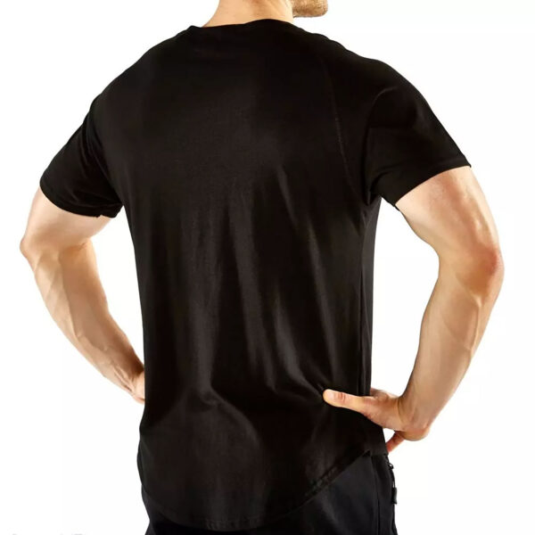 An individual in an ATX® Training Shirt BLACK faces away from the camera, hands on hips. The shirt fits snugly, emphasizing their physique against a plain white backdrop.