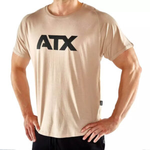 A person wearing a beige T-shirt with ATX printed in bold black letters on the front. The person has their hands on their hips and is paired with black pants. The background is plain and white.