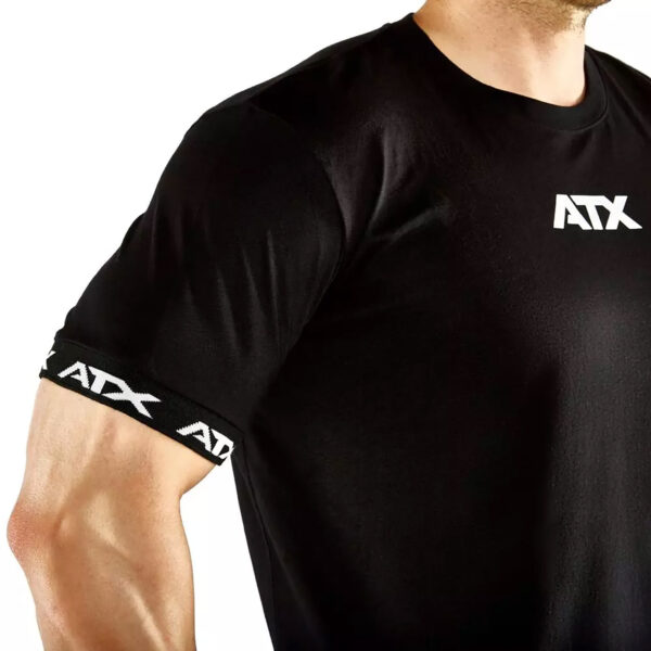 Close-up of a person in an ATX® Training Shirt BLACK, featuring the ATX logo on the chest and sleeve. The image emphasizes the muscular upper arm and chest, showcasing both physique and shirt design.