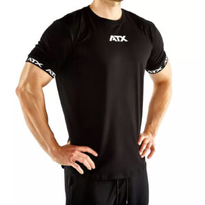 A man confidently poses with hands on hips, wearing a black ATX® Training Shirt featuring ATX on the chest and sleeves, set against a white background.