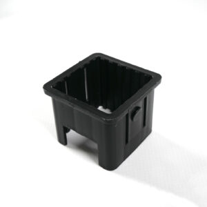 An Upright Sleeve Insert 40x40, a black rectangular plastic container with open ends and a button-like feature on one side, stands on a white surface.