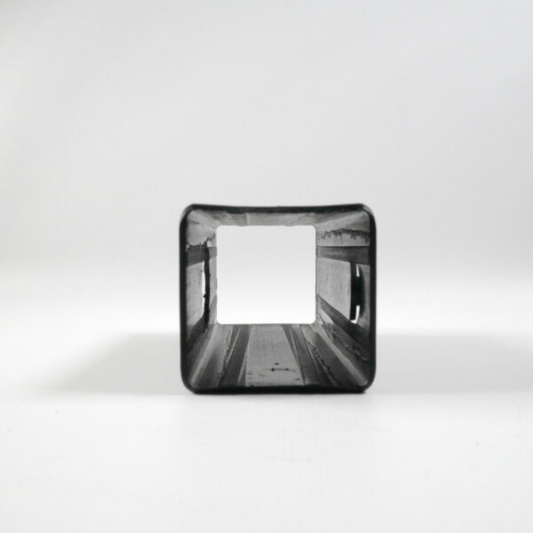 The Upright Sleeve Insert 40x40x120, a square metal pipe with an open end facing the viewer, reveals its hollow interior against a white background. It casts a soft shadow on the surface.