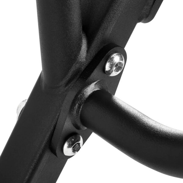 Close-up of a black metal frame with three shiny silver bolts securing two intersecting bars, reminiscent of a trap bar. The surface has a matte finish, and the image emphasizes the sturdy construction and minimalist design of the structure.