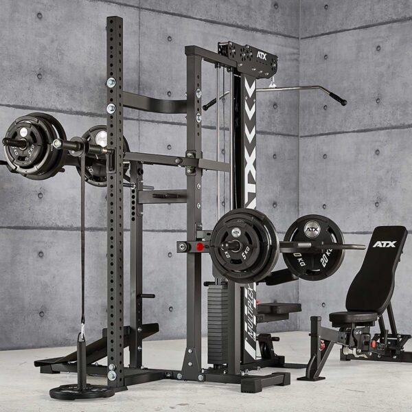 The ATX® MultipleX Multi Gym - 700 is a home gym setup, complete with a multifunctional weightlifting station. It includes a squat rack, bench press, cable pulleys, and various weight plates attached and stored on the equipment against a concrete wall background.