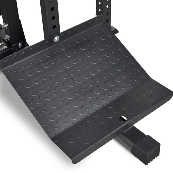 Close-up of the black, textured steel foot plate from the ATX® MultipleX Multi Gym - 700. It features a diamond pattern design for secure footing and grip, commonly found in gym equipment.