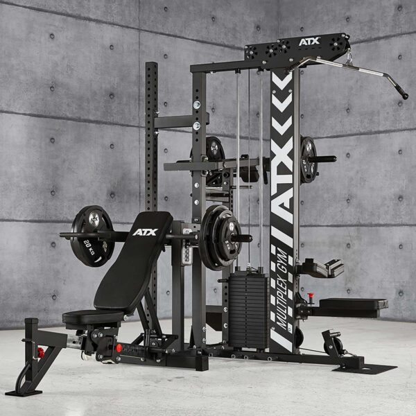 The ATX® MultipleX Multi Gym - 700 is a multifunctional home gym set with a bench, weight plates, pulleys, and pull-up bar. It features a black design with ATX branding against a gray concrete wall in a spacious room.