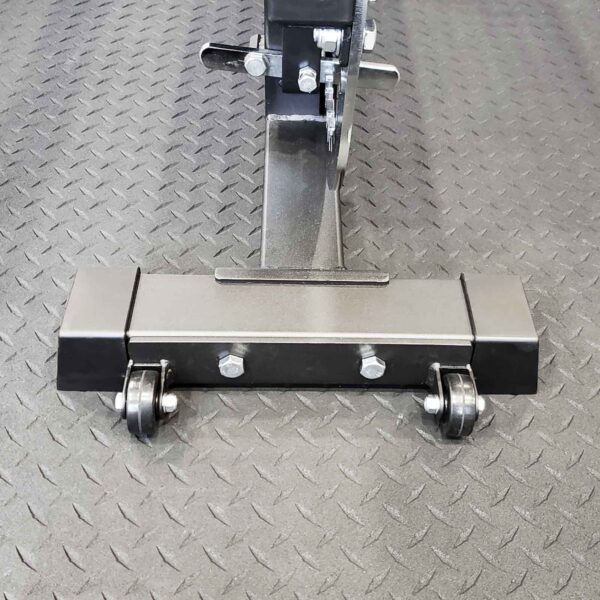 Close-up of the Ironmaster Wheelkit for Super Bench PRO with a black base on a textured rubber mat, featuring two front caster wheels and metal bolts for stability.