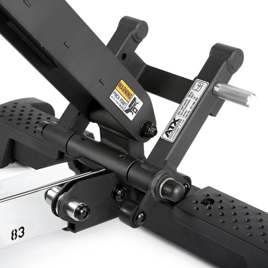 Close-up of a black adjustable bench support mechanism, highlighting its fid bench versatility. The image showcases various metal components, warning labels, and a handle grip. The perforated platform ensures traction, while the sleek bench frame provides sturdy support for any workout routine.