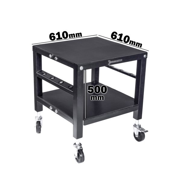 The Ironmaster QLDB Stand PRO is a black wheeled table with a square top measuring 610mm by 610mm and stands 500mm high. It includes a lower shelf for storing Ironmaster adjustable dumbbells and is labeled WORKMASTER on the side.