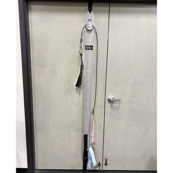 The Spud Inc Door Jammer Pulley System is neatly installed on a light-colored door with ropes and carabiners, while a black door handle is visible on the right side of the door.