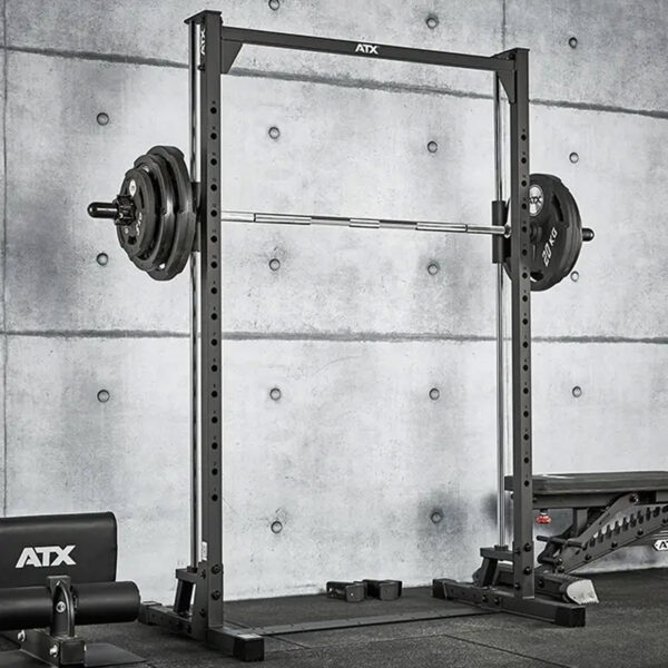 The ATX® Smith Machine 500, designed for low ceilings at 198 cm, is set up in a gym with a concrete backdrop, alongside a bench and other exercise equipment.