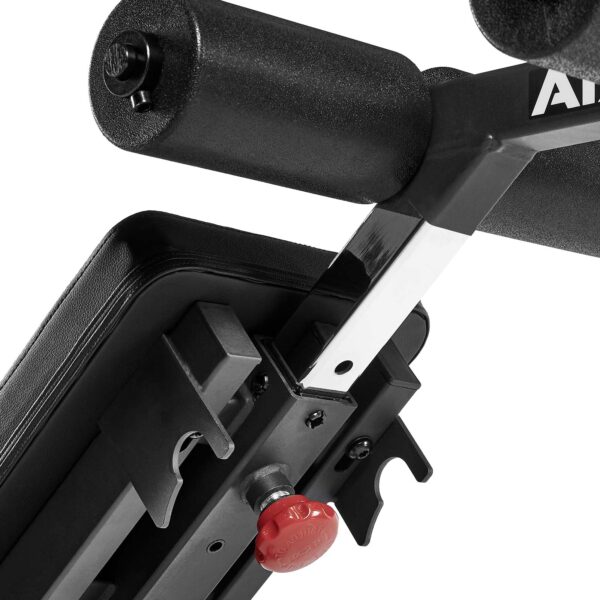 Close-up of the ATX® AB Attachment black adjustable gym bench mechanism, featuring a padded leg support and a red adjustment knob for incline settings. The metal structure with foam padding is visible.