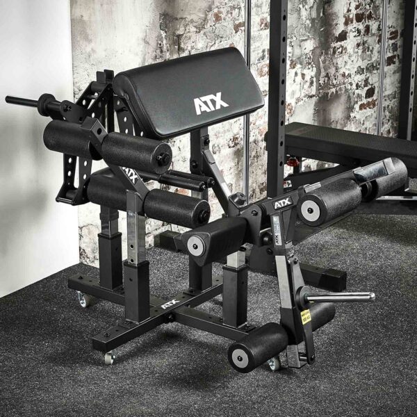 The ATX® Attachment Storage Rack, set against weathered white bricks and on a dark carpet, features a padded seat, adjustable arm and leg supports, plus multiple handles and levers.