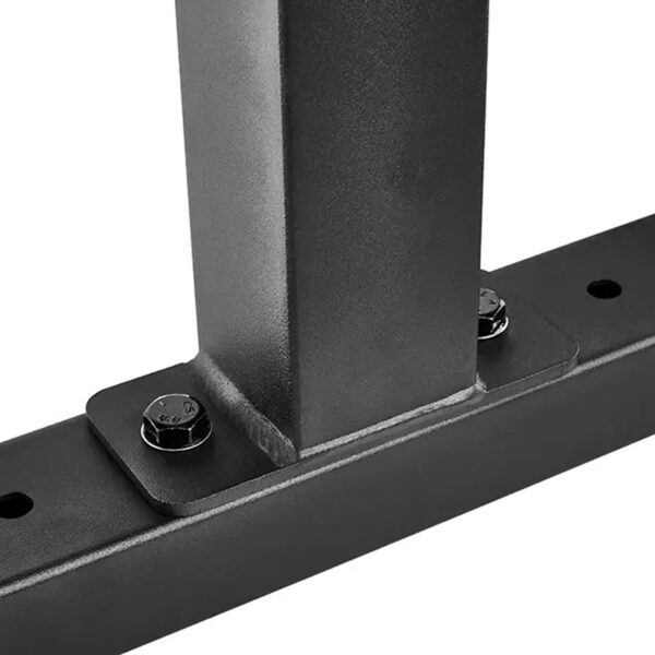 Close-up of the ATX® Attachment Storage Rack, featuring a black metal frame with a vertical beam connected to a horizontal base using two visible bolts, showcasing a sturdy industrial design.