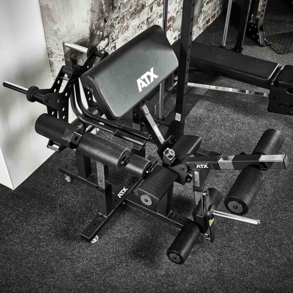 The ATX® Attachment Storage Rack, with padded rollers and adjustable settings, is placed on a carpeted floor against a brick wall.