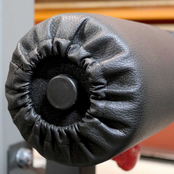 Close-up of the Foam Roller Cover 65mm in black leather, with a central black button and gathered stitching. A slightly blurred background emphasizes focus on the cushion roll.