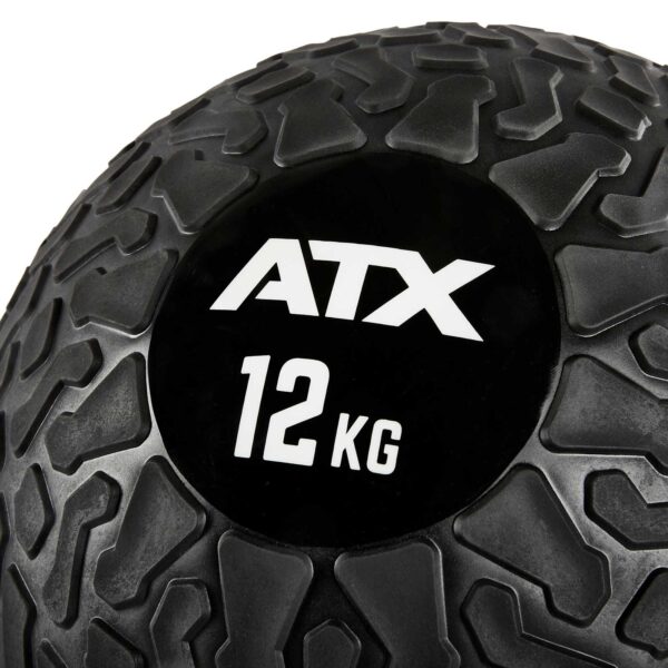 Close-up of an ATX® Slam Ball with a textured black surface and a rugged pattern. The brand ATX and weight 12 KG are displayed in white on its smooth circular patch.