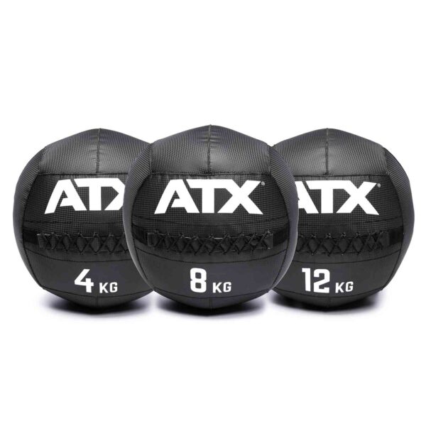 Three black ATX® Wall Balls PVC are lined up side by side with weights of 4 kg, 8 kg, and 12 kg. They each feature visible stitching and a textured surface.