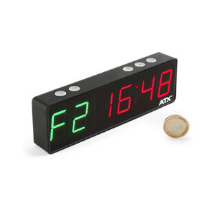 A digital clock displaying F2 in green and 16:48 in red. The clock is rectangular and black with buttons on top. A coin is placed beside it for scale.