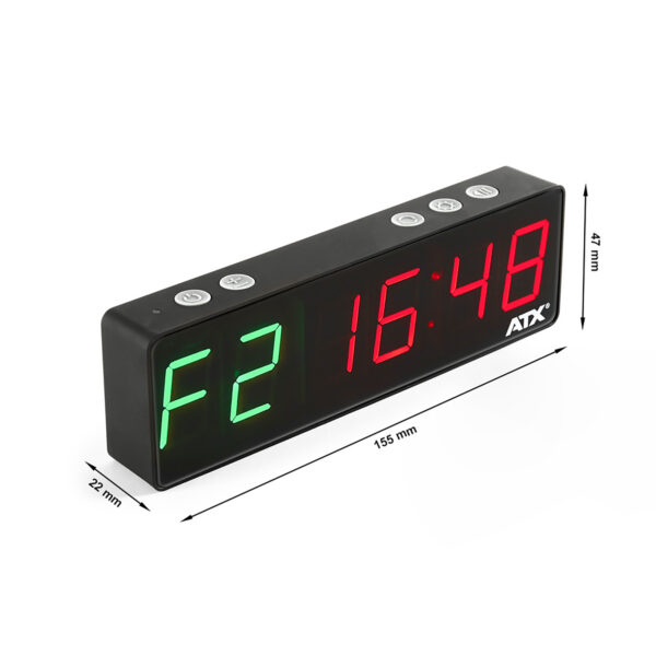 A rectangular digital clock with a black frame displaying F2 in green and 16:48 in red. Three buttons are on top, and dimensions are shown as 155 mm width, 47 mm height, and 22 mm depth. Branding ATX is visible.