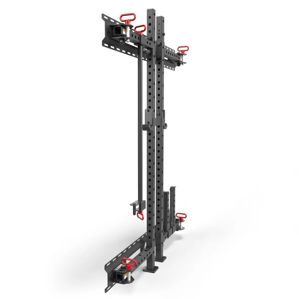 The ATX® Folding Squat Rack 500 is a black metal, wall-mounted rack with adjustable holes and integrated red hooks and handles for securing equipment. Its compact, space-saving, and displayed at an angle on a white background.