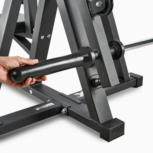 A hand adjusts a black, cylindrical handle on the ATX® Cable Lat Pull Down Machine, connected to a robust gray gym frame. The machines base is in view, showing bolts and the manufacturers logo.