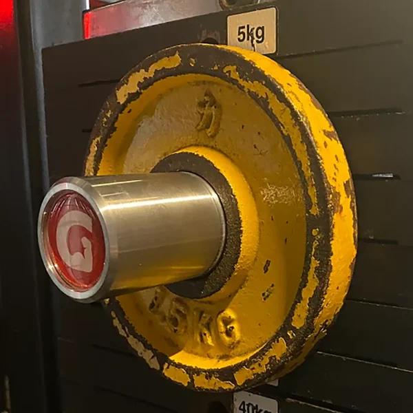 Close-up of a GymPin 2 Original with a yellow 5kg weight plate and metal pin inserted, showcasing a red G end. Its set against the machines black background with white slots for weight levels.