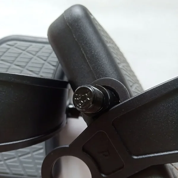 The image features a close-up of the Spin Bike Pedal 9/16, highlighting its textured, non-slip surface. The central axis bolt and part of the crank arm are visible amid a blurred, light-colored background.