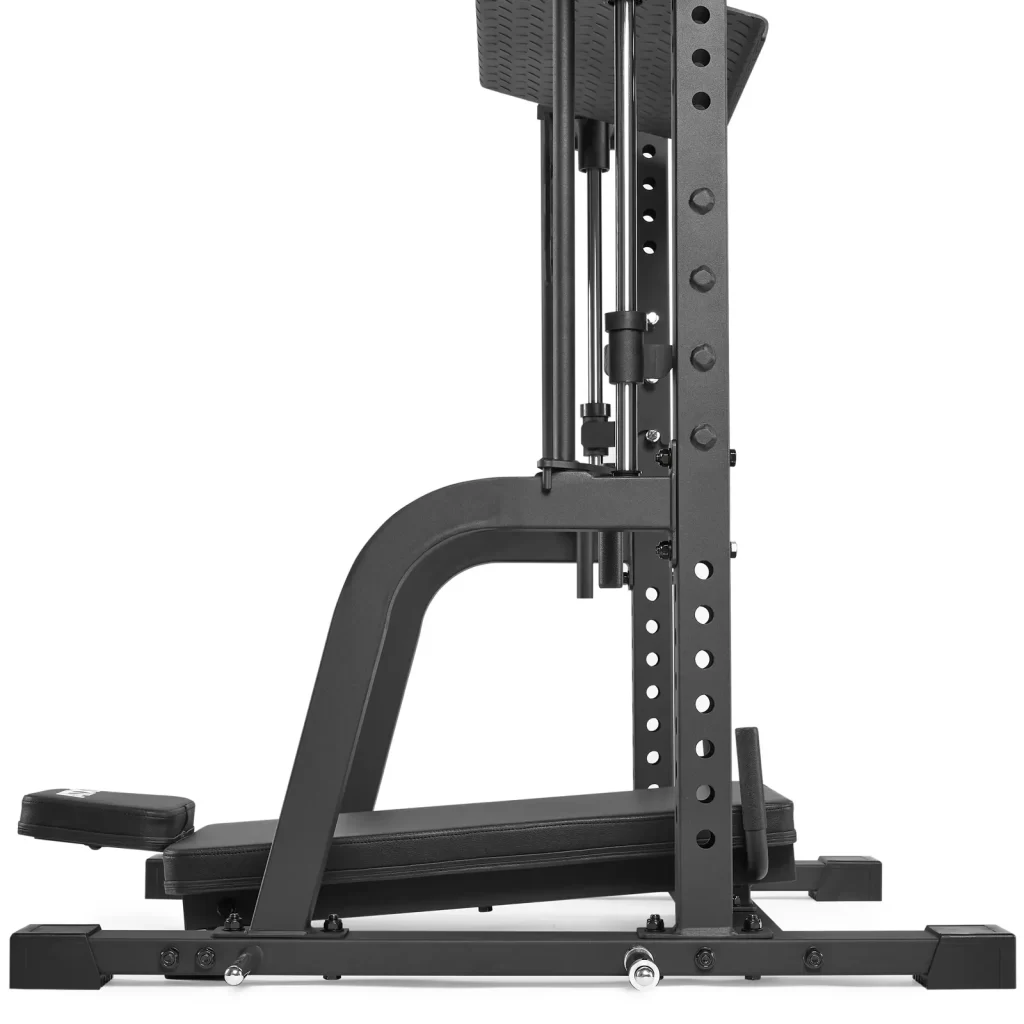 Side view of a home gym machine with a black metal frame, adjustable benches, and weight stack. It features a footrest and several holes for height adjustments, designed for strength training exercises.